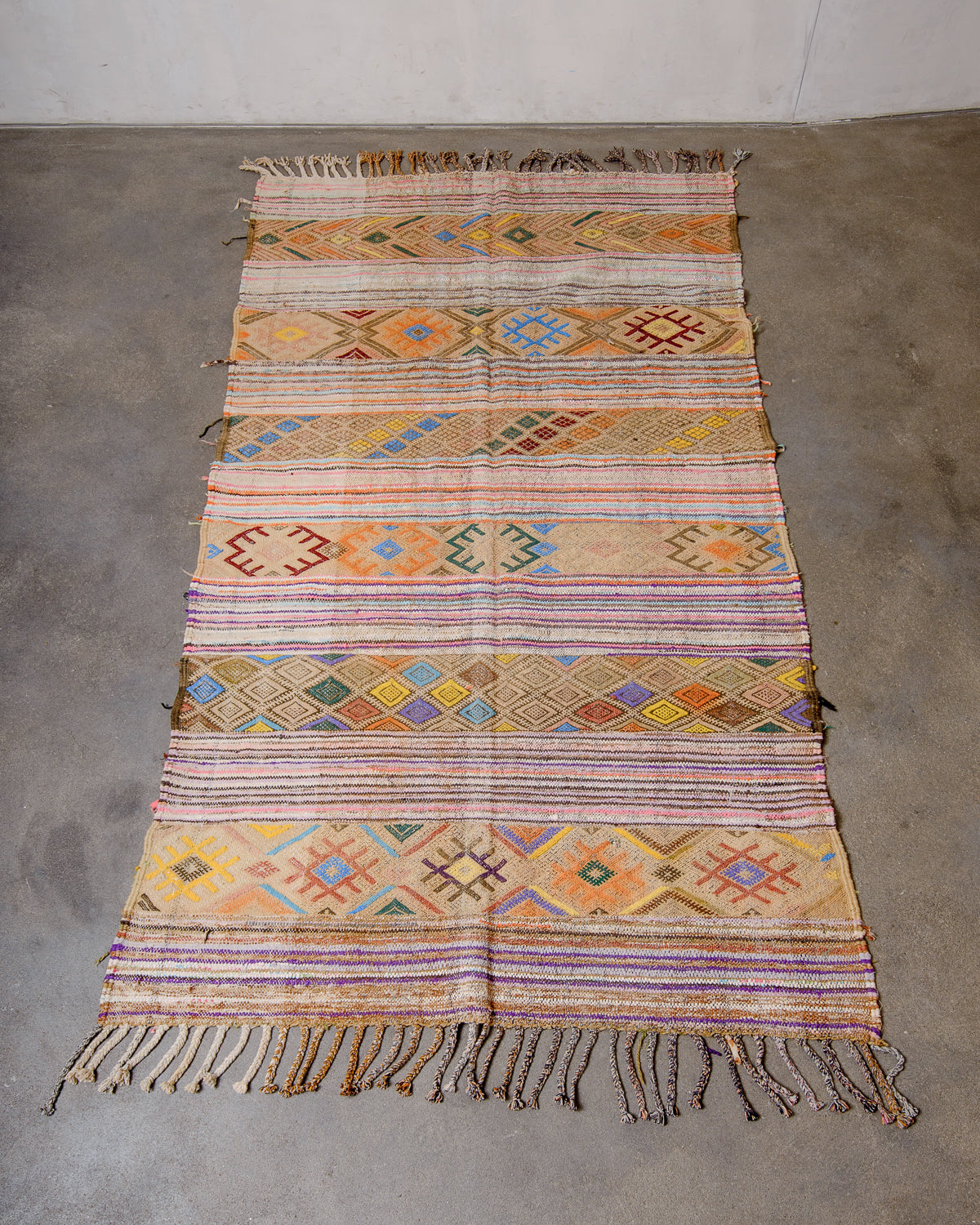 Berberlin vintage moroccan Kelim rug with colourful details being laying flat on concrete floor.